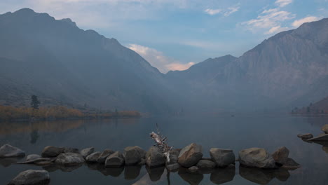 boats cruising at sunrise on convict lake in fog with laurel mountain in background