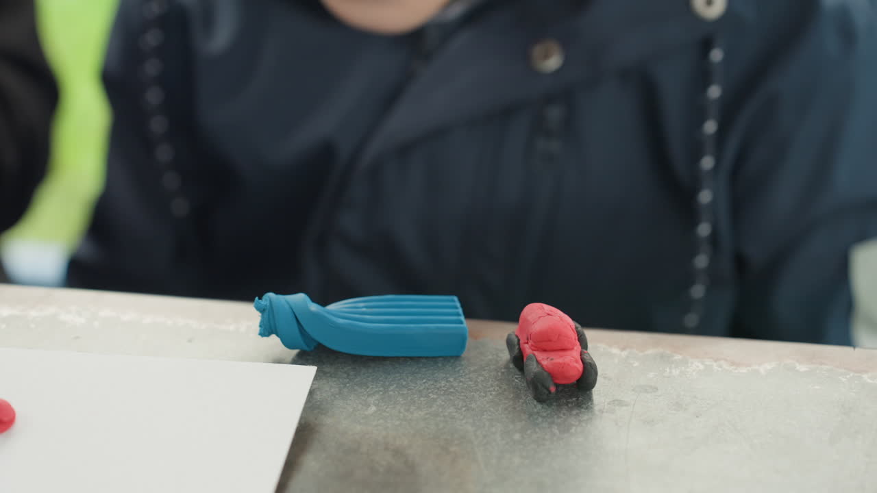 Child at desk with erasers preparing back to school supplies, closeup of small student arranging blue pencil case and red eraser on tabletop, candid outdoor light, focused hands, textured surface
