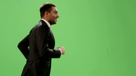 happy businessman in a suit is running on a mock-up green screen in the background.