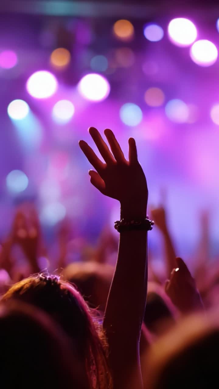 Una folla in delirio alza le mani emozionata sotto le vivaci luci del palco, catturando l'atmosfera elettrizzante della musica dal vivo e della festa in questo momento ipnotico