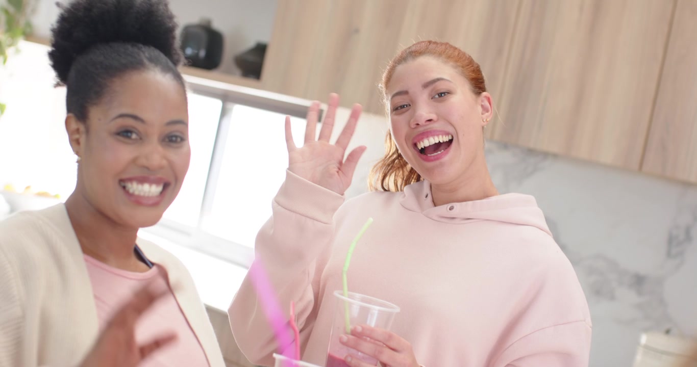 Amiche di diverse etnie che sorridono, la telecamera si allontana, le donne agitano le tazze, salutando la telecamera in cucina.