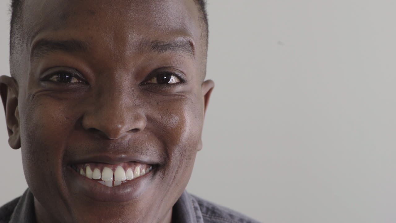 joven afroamericano feliz sonriendo emocionado disfrutando del estilo de vida éxito en fondo en blanco copyspace de cerca