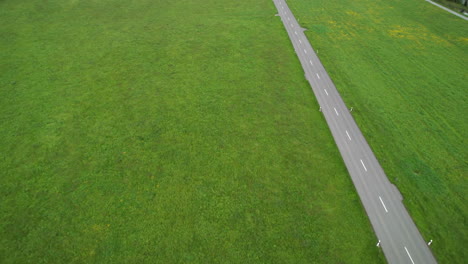 lonely electric car drives on road across green meadow