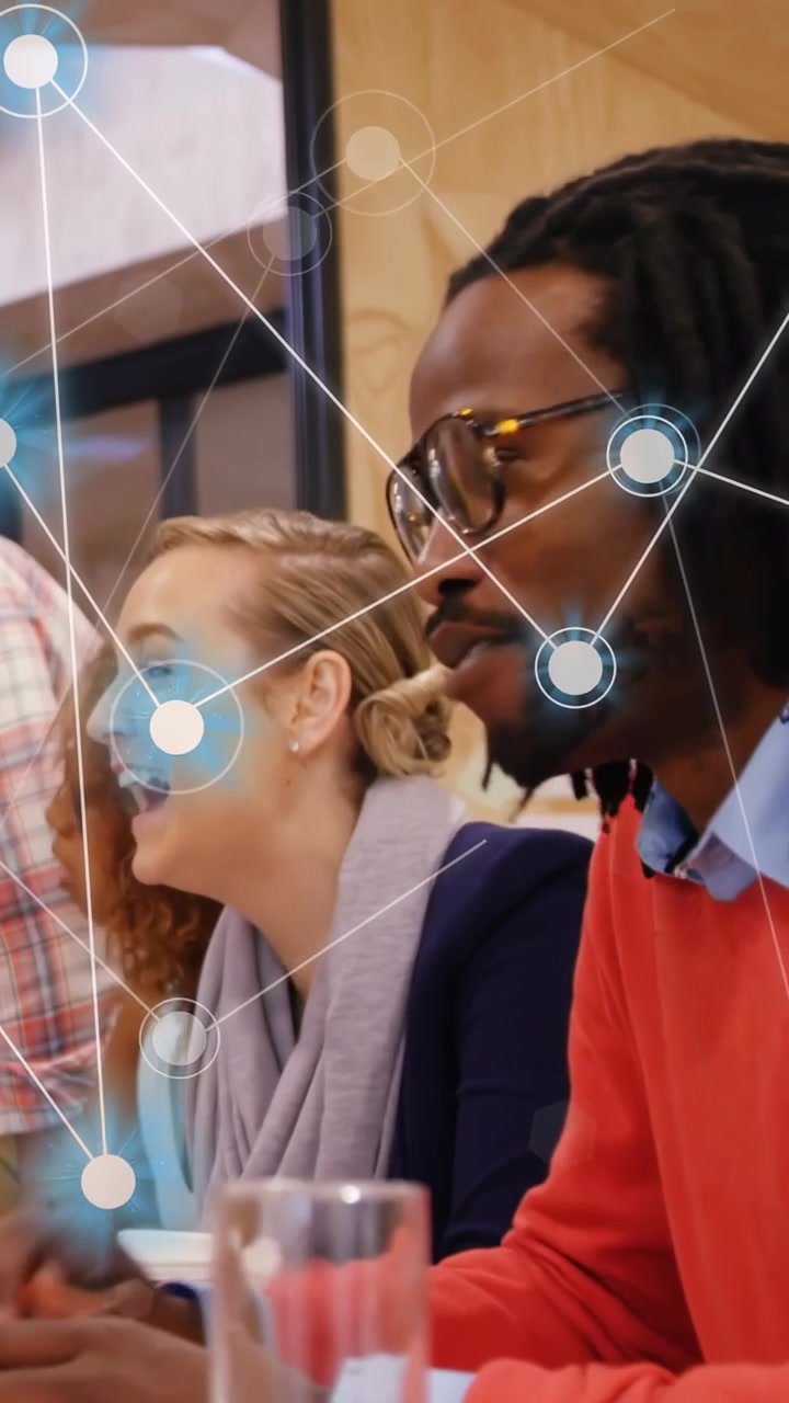 Vertical video: Panning down man speaking and team reacting and planning, tech nodes touching them