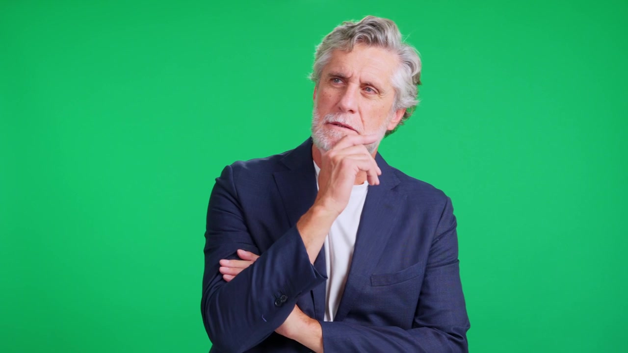 Mature worried businessman thinking against green screen