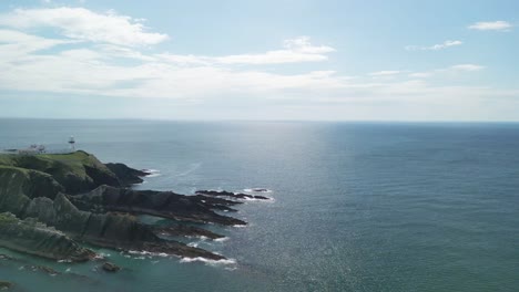 an aerial footage, slide over galley head peninsula with a lighthouse in west cork, ireland on a sunny day