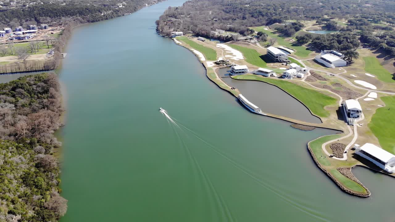 Aerial Austin Pennybacker Bridge - with small portion of bridge in view to start, turning left down river to pursue boat, long wake seen in water