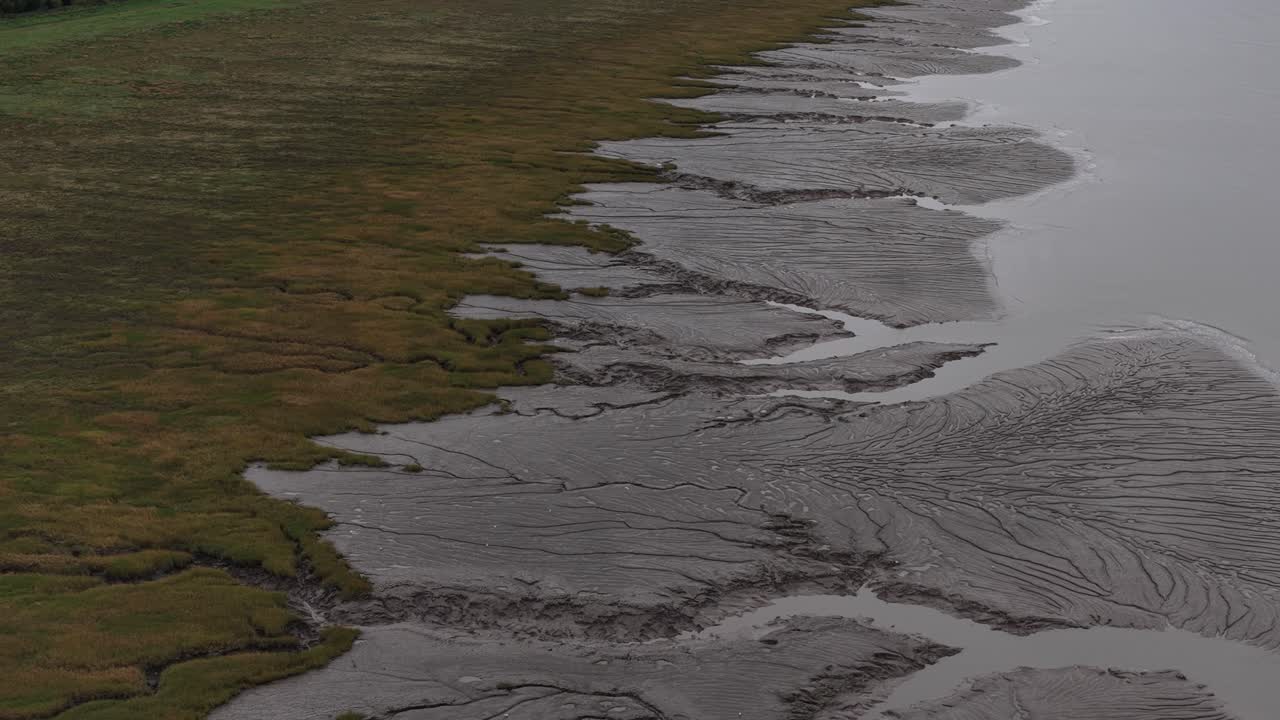 Aerial drone footage of the Portbury marshlands and coastline nature reserve, showcasing tidal wetlands, cloudy weather atmosphere, and tranquil coastal habitat along England’s western shores