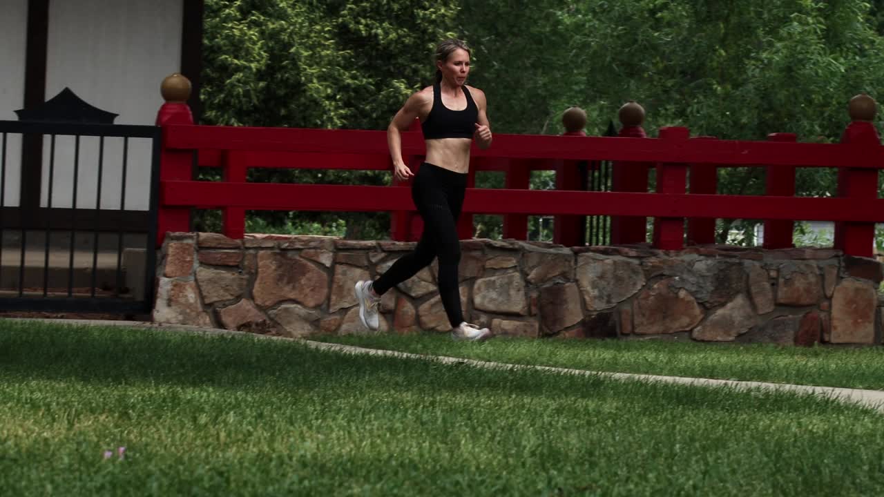 An athletic woman runs on park pathway into frame. Shot on gimbal