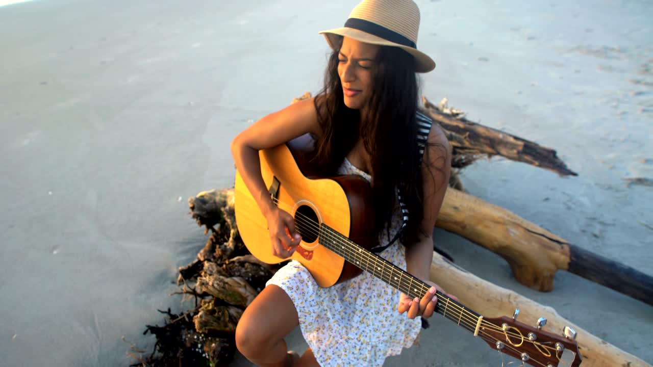 chica india americana cantando tocando la guitarra en la playa