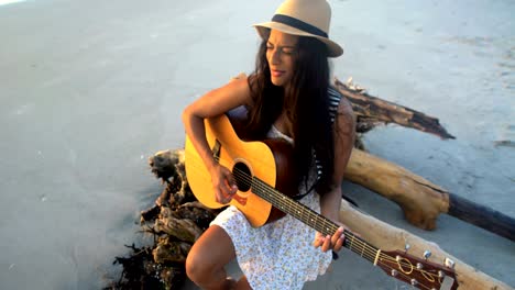 indian american girl singing playing guitar on beach