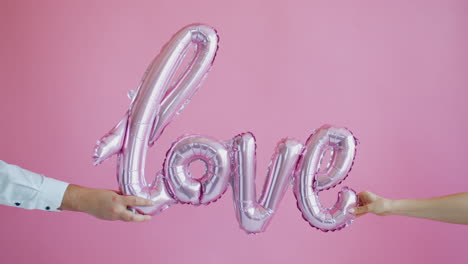 couple holding a pink love balloons