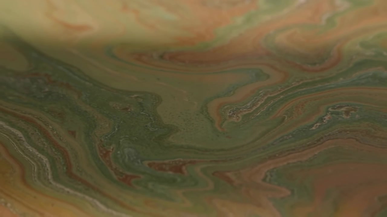 Abstract glossy marbled surface with flowing olive green, muted orange, and beige swirls, layered veins, and smooth organic curves forming calm decorative background with rich tonal depth