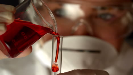 Scientist-pouring-red-liquid-into-test-tube