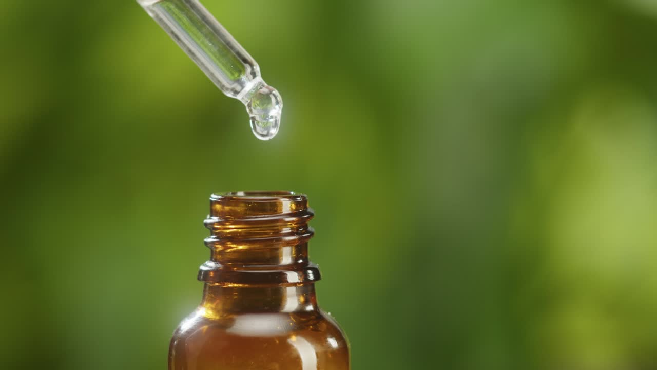goteo de aceite de pipeta en botella de primer plano, jugo de planta. hacer suero de aroma en fondo verde. goteo de extracto líquido, rutina de cuidado de la piel, aceite esencial de tratamiento, concepto de spa. medicina tradicional