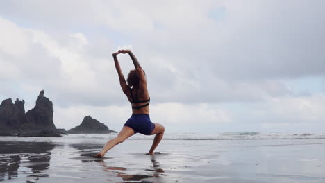 Con-Un-Tranquilo-Océano-De-Fondo,-Una-Mujer-Joven-Y-Delgada-Practica-Yoga-Y-Estiramientos-En-Cámara-Lenta,-Con-Los-Ojos-Fijos-En-El-Horizonte-Lejano.