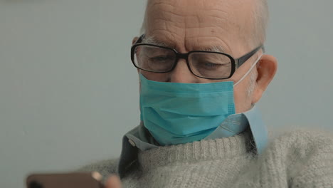 Portrait-Of-Elderly-Man-With-Face-Mask-Using-A-Smartphone