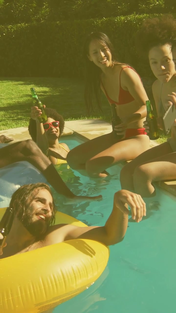 Video verticale: Amici che si rilassano in piscina, sollevano il telefono per un selfie mentre gli avvisi social suscitano sorrisi.