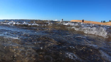 punto de vista desde dentro de las olas siendo azotado dentro de las olas rodeado de arena y burbujas y espuma de olas