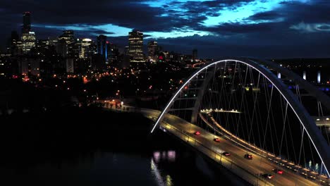 Aerial-drone-view-of-the-Edmonton-Walterdale-Bridge-over-the-North-Saskatchewan-River-during-a-summer-night-and-the-downtown-skyline-in-the-background