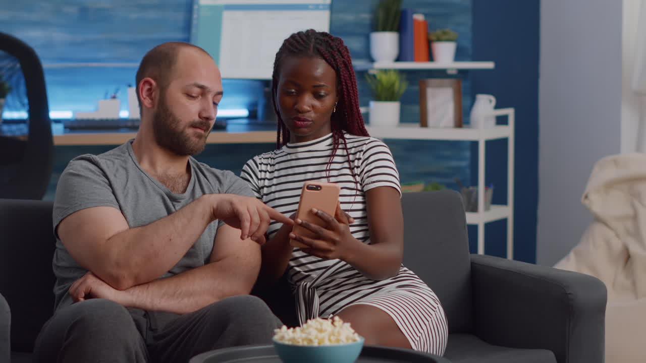 Interracial couple looking at smartphone screen at home