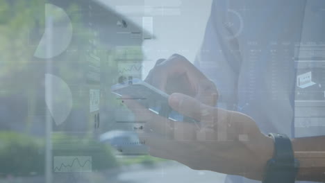animation of multiple graphs, trading board over midsection of biracial man using cellphone