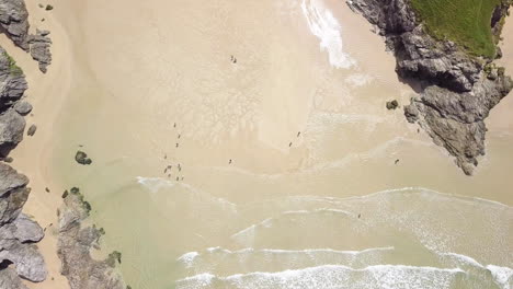 ocean waves on poly joke beach in summer - tourists at sandy beach tucked into a deep cove at low tide in cornwall, england