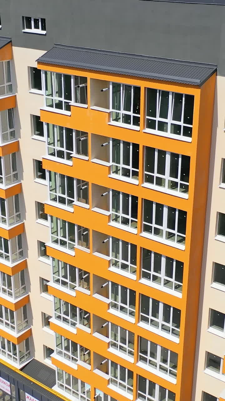 Modern office building in the city. Exterior of a new apartment building with colorful walls and large balconies. Top down drone movement. Vertical video