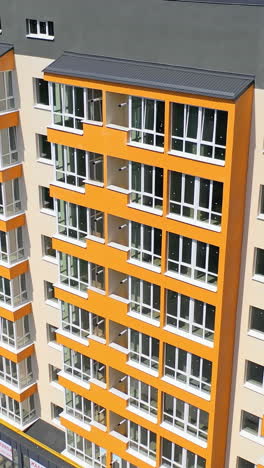 modern office building in the city. exterior of a new apartment building with colorful walls and large balconies. top down drone movement. vertical video
