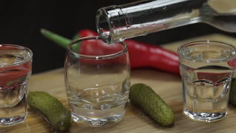 pour vodka into shot glasses placed on a wooden board