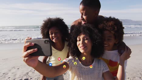Animation-Von-Mediensymbolen-über-Einer-Glücklichen-Afroamerikanischen-Familie,-Die-Am-Sonnigen-Strand-Ein-Selfie-Macht