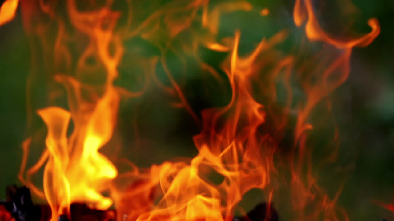 Bright fire and flames burn in hot fireplace. Beautiful orange tongues of flame on wooden logs for barbecue. Close-up.