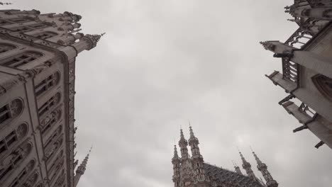 Low-angle-shot-of-gothic-architectural-town-hall,-Saint-Peter's-Church-and-guild-building-on-the-Grand-Square-in-Leuven,-Belgium