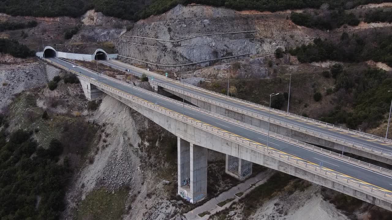 vista aérea de coches en la carretera del puente en la montaña griega con túnel durante el anochecer en grecia