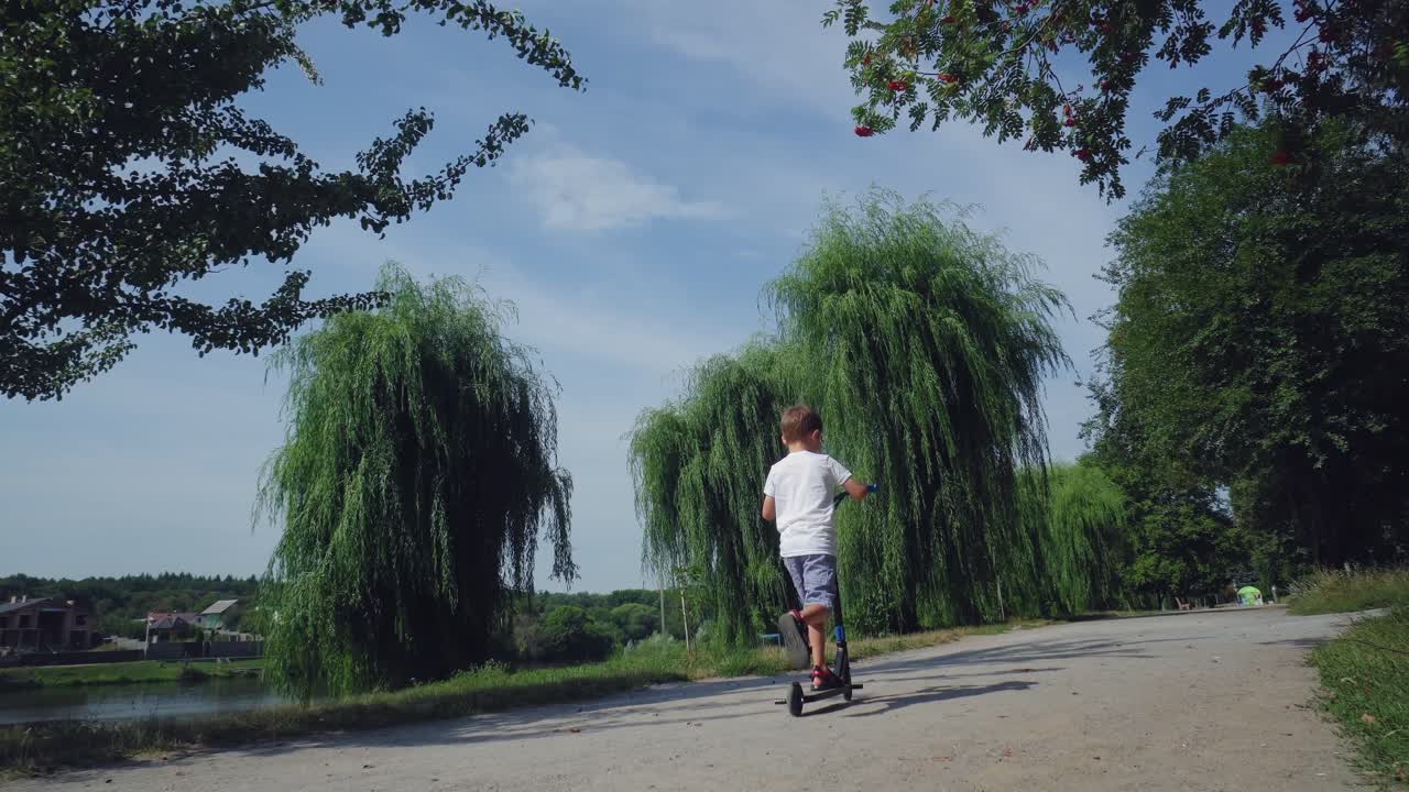 한 소년이 도시 공원에서 스쿠터를 타고 있다.