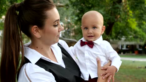 happy childhood, cute boy in suit on hands of mother