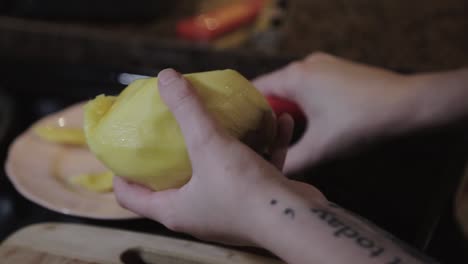 a woman slicing a ripe mango with red knife and placing it in a plate at the kitchen - close up shot