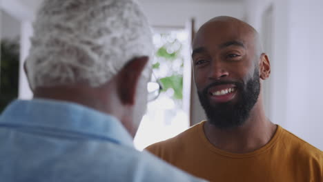 Senior-Father-Talking-And-Laughing-With-Adult-Son-Indoors-At-Home