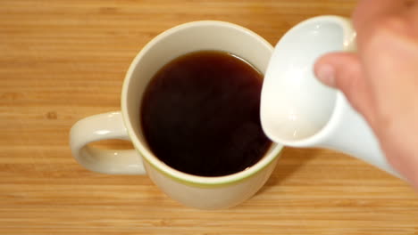 milk being poured into a cup of tea