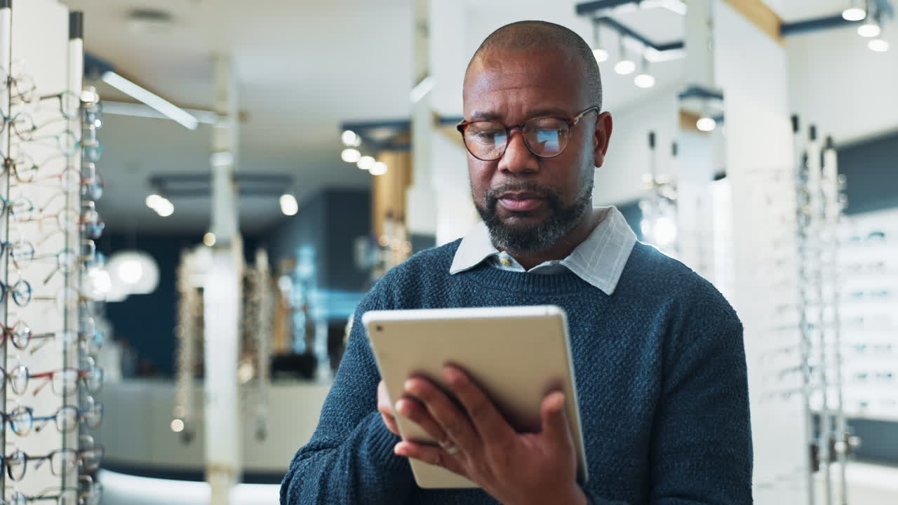 Man wearing glasses looking at tablet in an opticians store