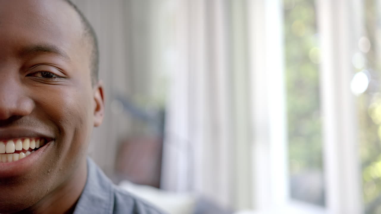 Half portrait of happy african american man in living room smiling, copy space, slow motion