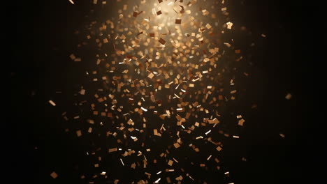 golden confetti falling on a dark background with spotlight