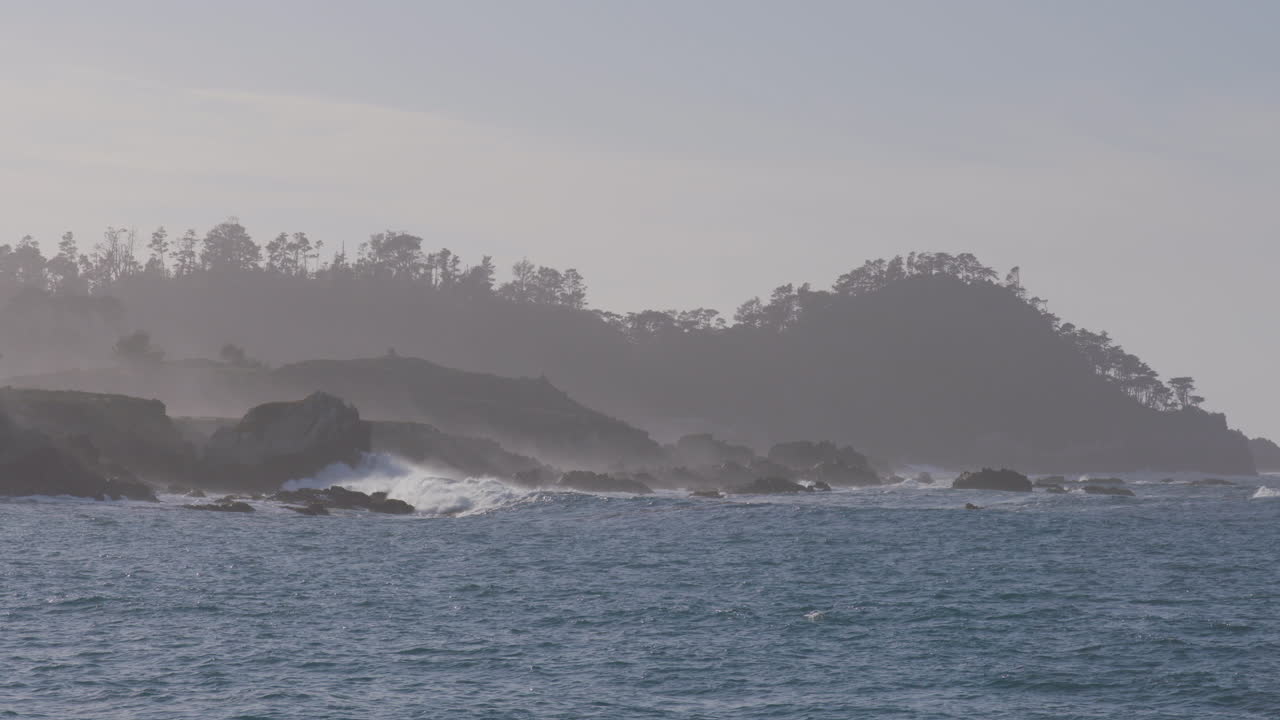 마리나 스테이트 비치 몬테레이 베이 캘리포니아에 위치한 안개가 자욱한 산 배경으로 바위 해안에 충돌하는 파도의 슬로우 모션 샷