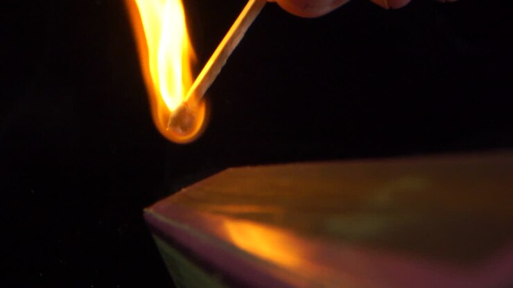 Tændstikflamme i slow motion. Antændelse og afbrænding af en tændstik på siden af æsken, sort baggrund.