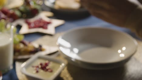 라마단 기간 동안 매일 단식을 깨는 iftar 식사를 위해 집에서 이슬람 가족 테이블에서 날짜를 먹는 사람