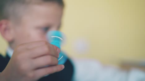 schoolboy plays with blue plastic spinner in room closeup