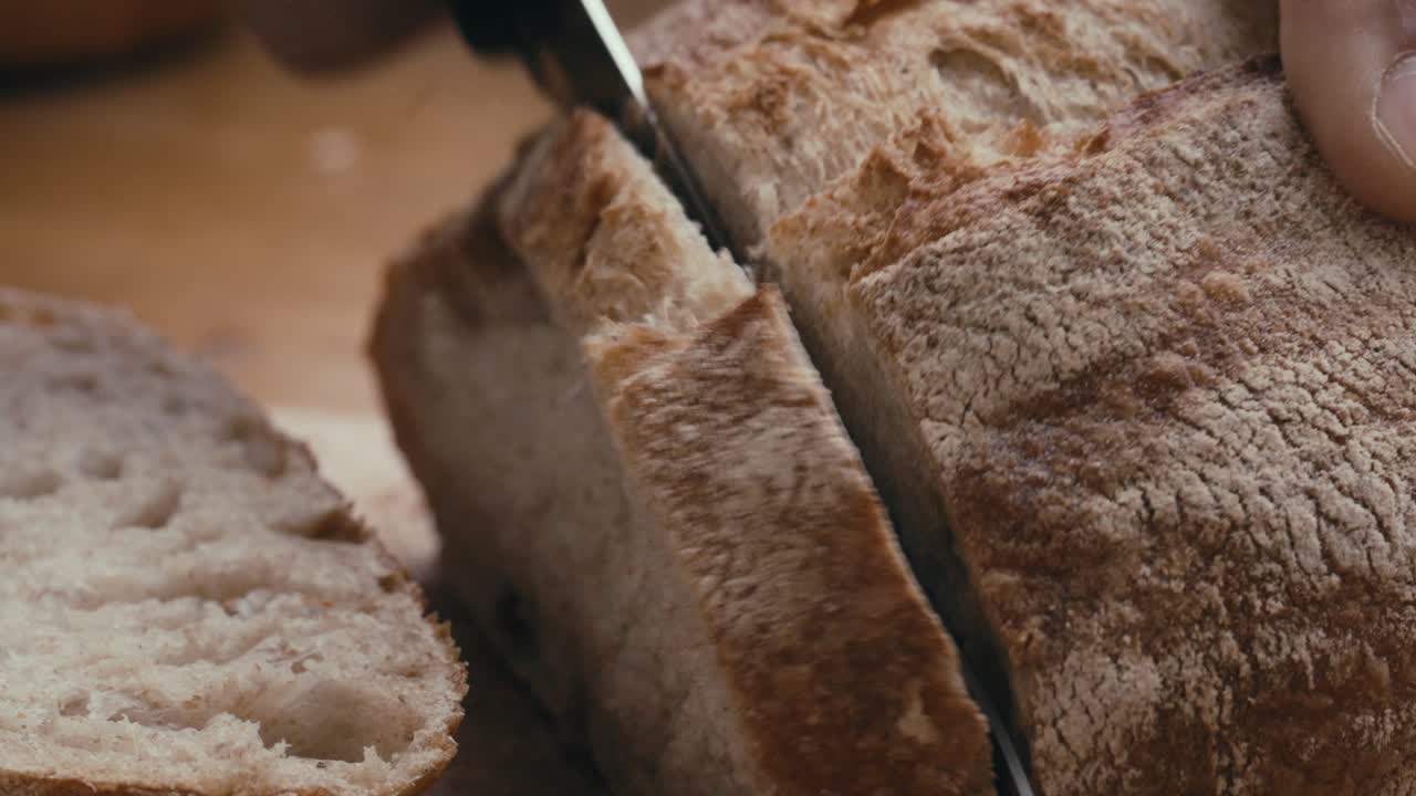 Hands Cutting Slice of Crusty Artisan Bread with Knife