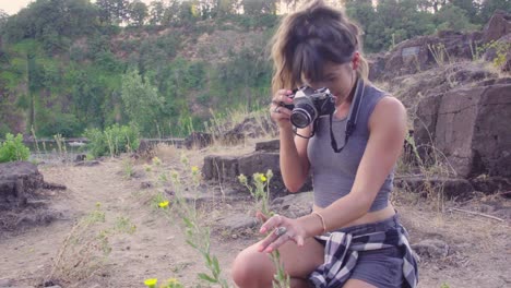 linda chica hipster tomando fotos de flores en una cámara de cine