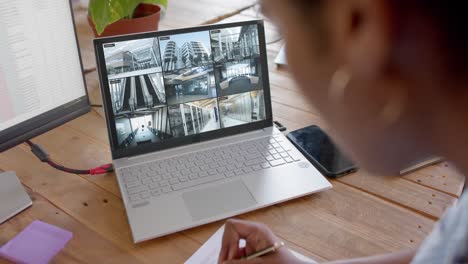 African-american-female-security-officer-watching-business-cctv-camera-views-on-laptop,-slow-motion