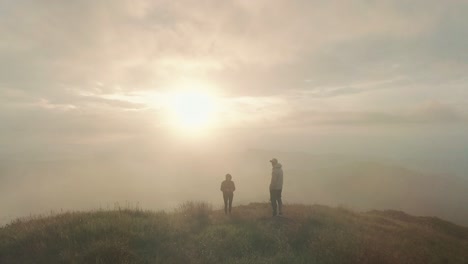 the man and woman are standing on the top of mountain against the sunrise